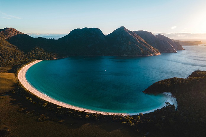 Aerial view of Wineglass Bay in Tasmania featuring its iconic crescent-shaped beach and turquoise waters